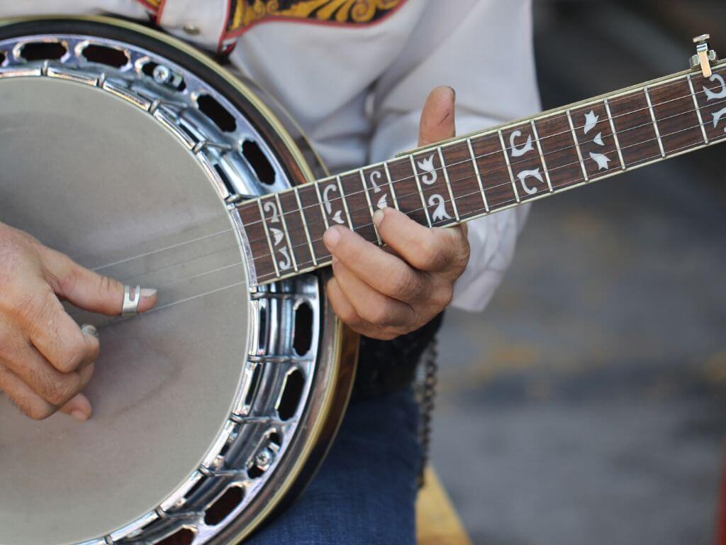 A close-up picture of a mans hands playing a banjo