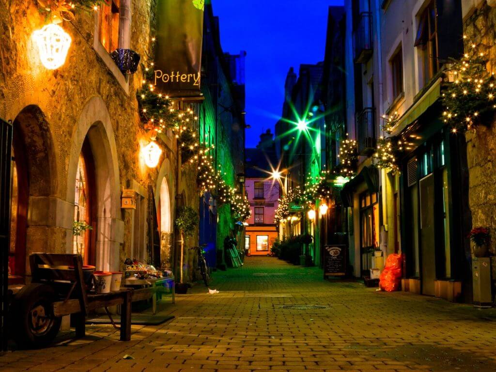 A night time shot of a narrow street lit by lights in Galway City, Ireland