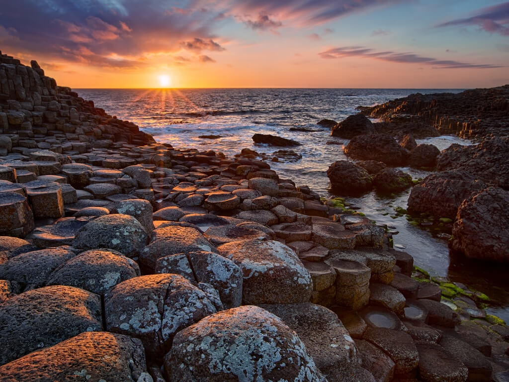 A sunset picture of the Giant's Causeway columns at the water's edge in Northern Ireland