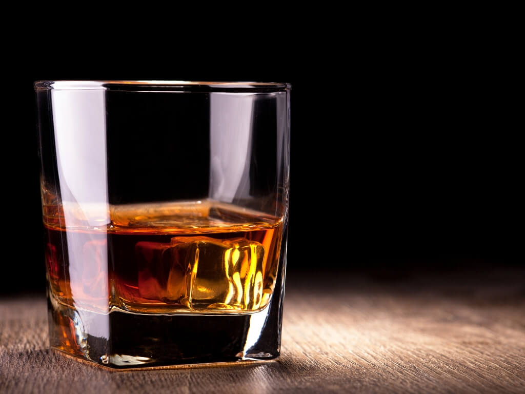 A picture of a glass of Irish Whiskey on a wooden table with a black background