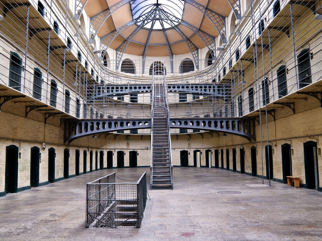 A picture inside Kilmainham Gaol, Dublin, Ireland, with cell door centred around an atrium with two levels of metal stairs and balconies