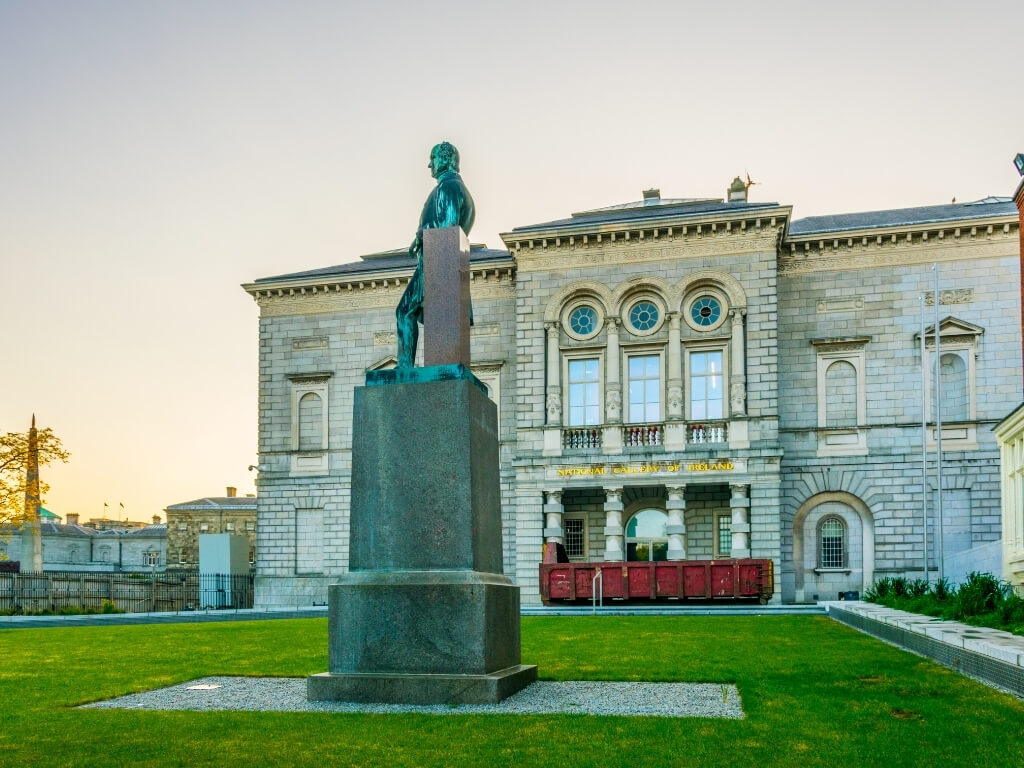 A picture of a statue outside the National Gallery of Ireland with the main building in the background