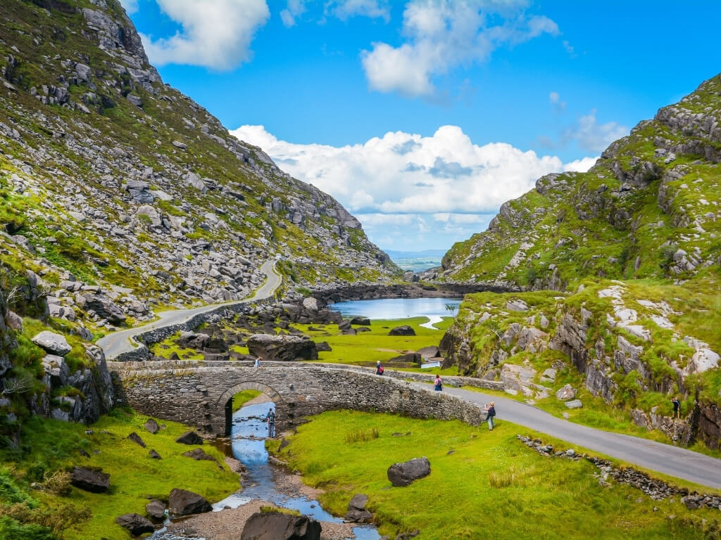 A picture of people crossing a bridge in the Gap of Dunloe in Ireland on a sunny day