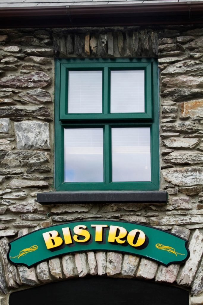 A picture of a green and yellow bistro sign on a traditional stone wall