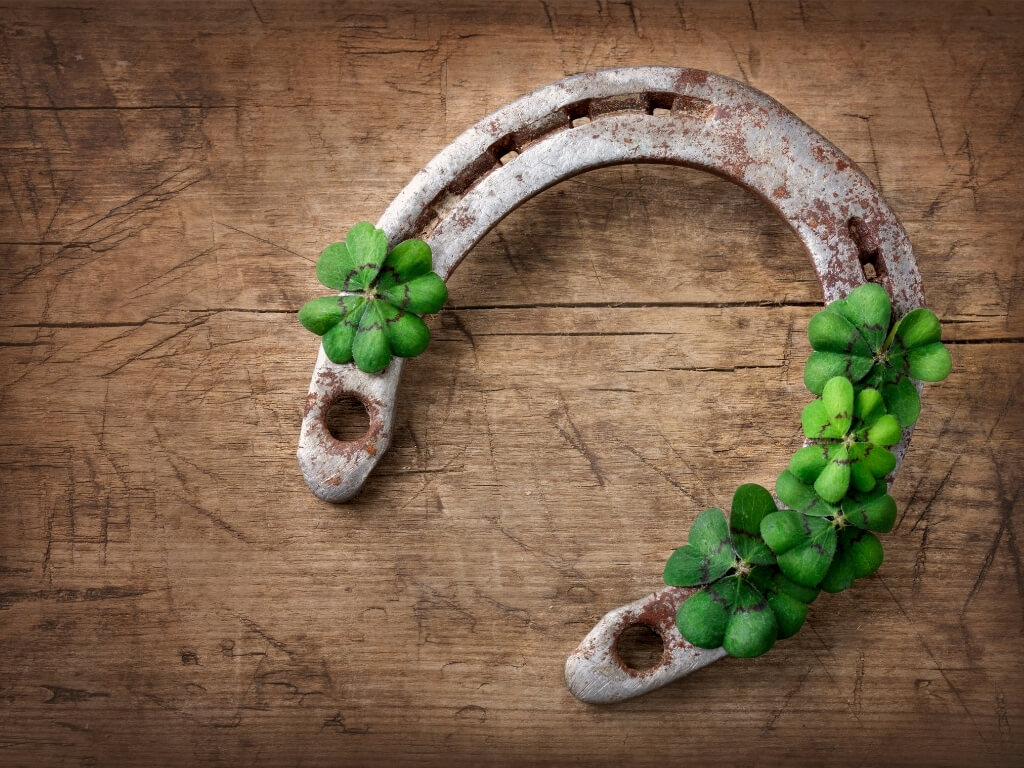 A picture of a horseshoe on wood with a few shamrocks on it