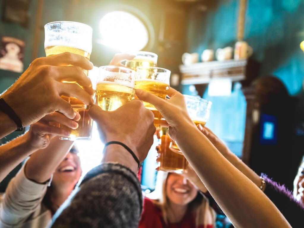 A group of people in a pub raising their pint glasses in a cheers motion