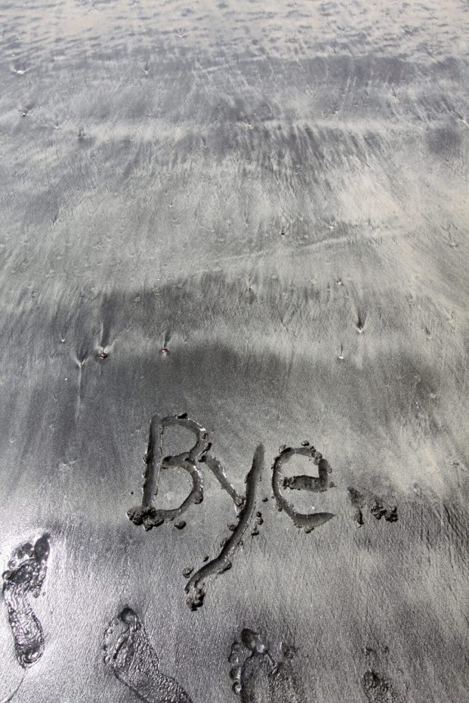 The word "bye" written in sand on a beach