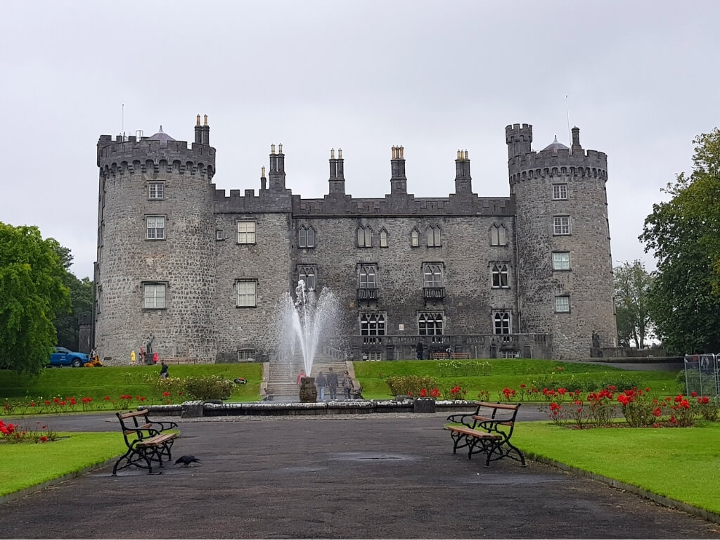 A picture of Kilkenny Castle with a fountain in front