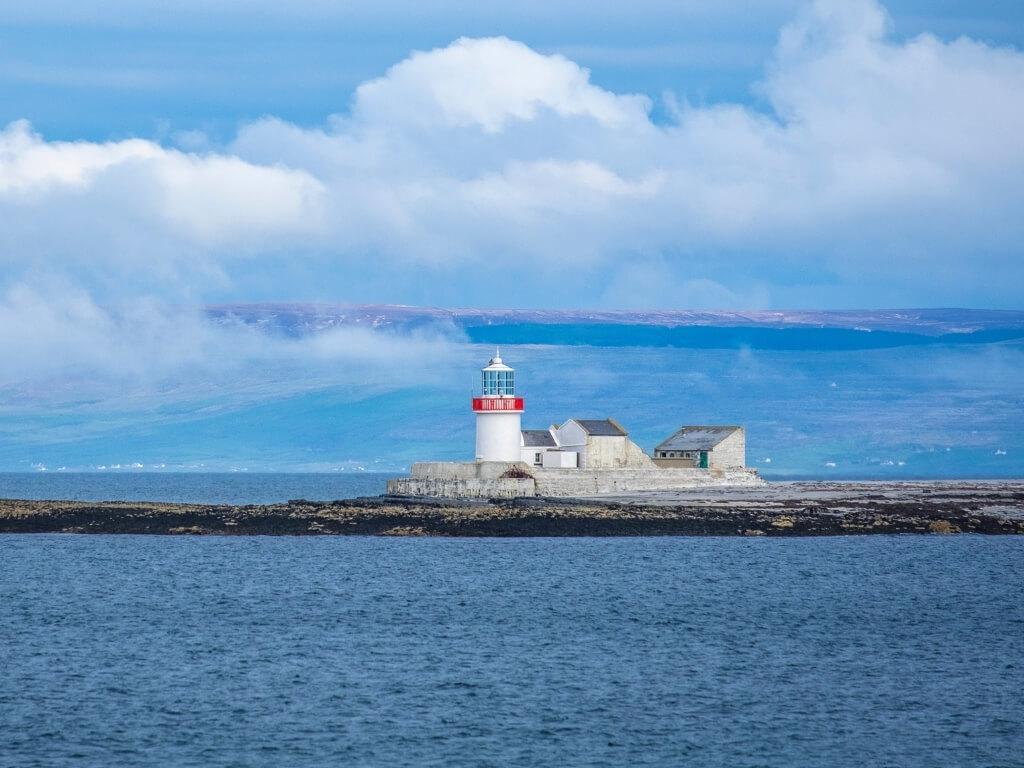 A picture of the The Eeragh Lighthouse on the Aran Islands, Galway surrounded by water and with mountains in the background
