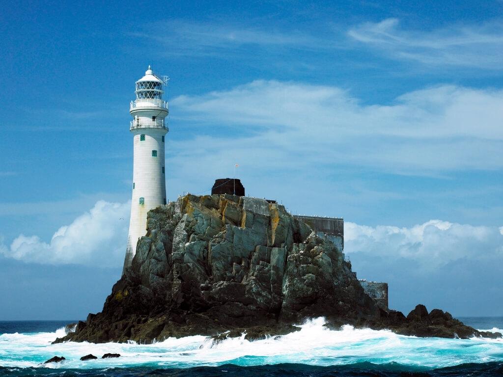 A picture of the tall Fastnet Lighthouse standing on its rocky island off-shore, one of the best lighthouses in Ireland to see