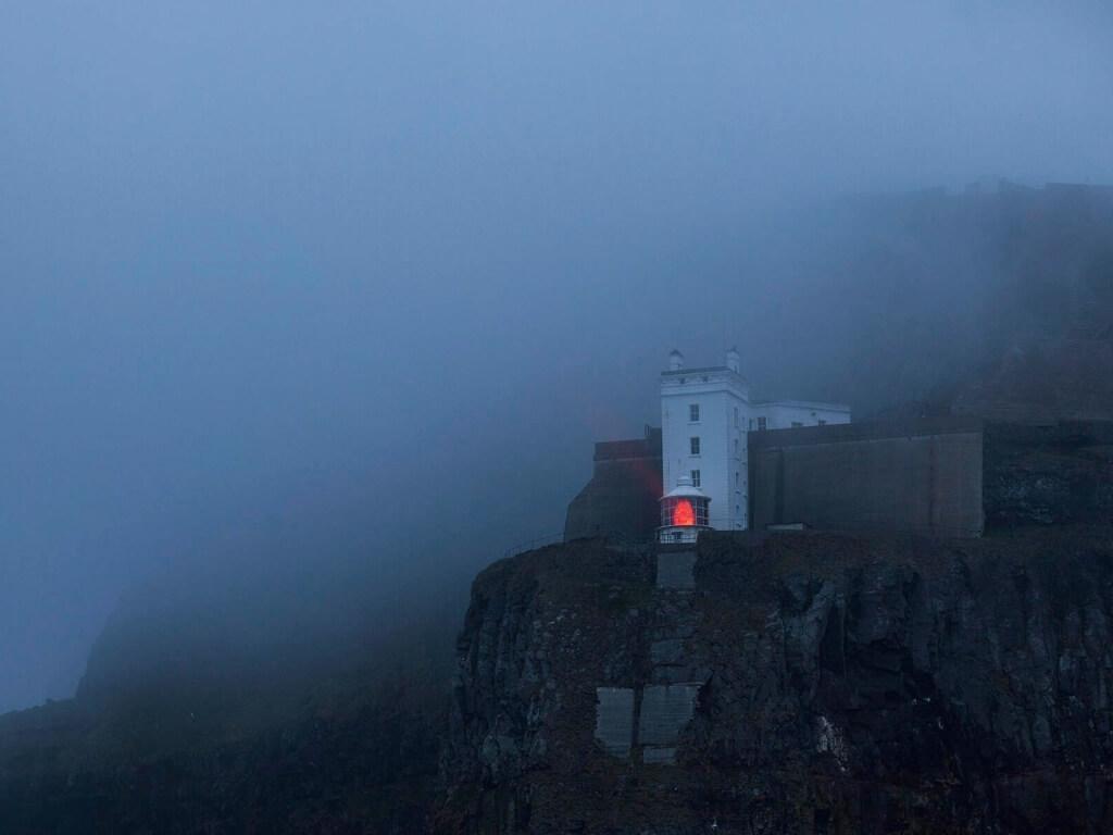 A picture of the Rathlin West Lighthouse shining its upside down beacon in foggy conditions