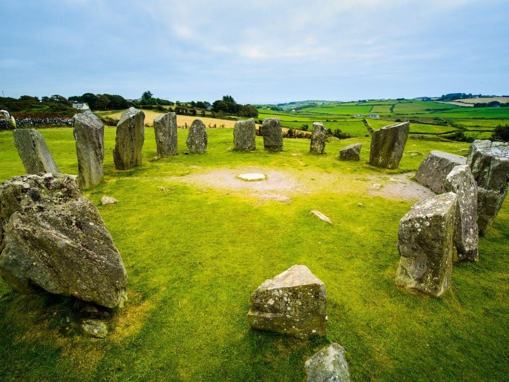 A picture of the Drombeg Stone Circle in County Cork, with lush green fields in the background