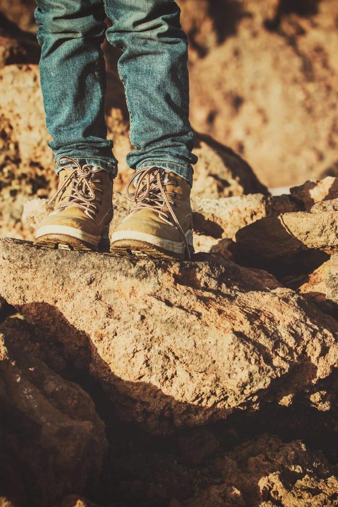 A picture of a kid in hiking boots standing on some rocks