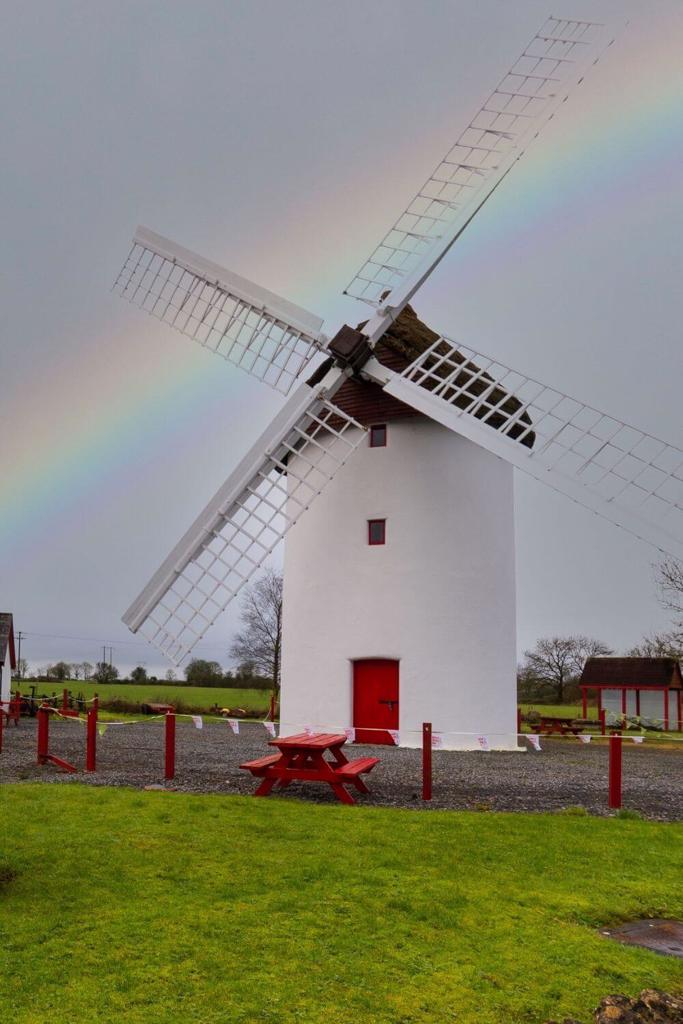 A picture of the Elphin Windmill in Roscommon with a grey sky and rainbow behind it