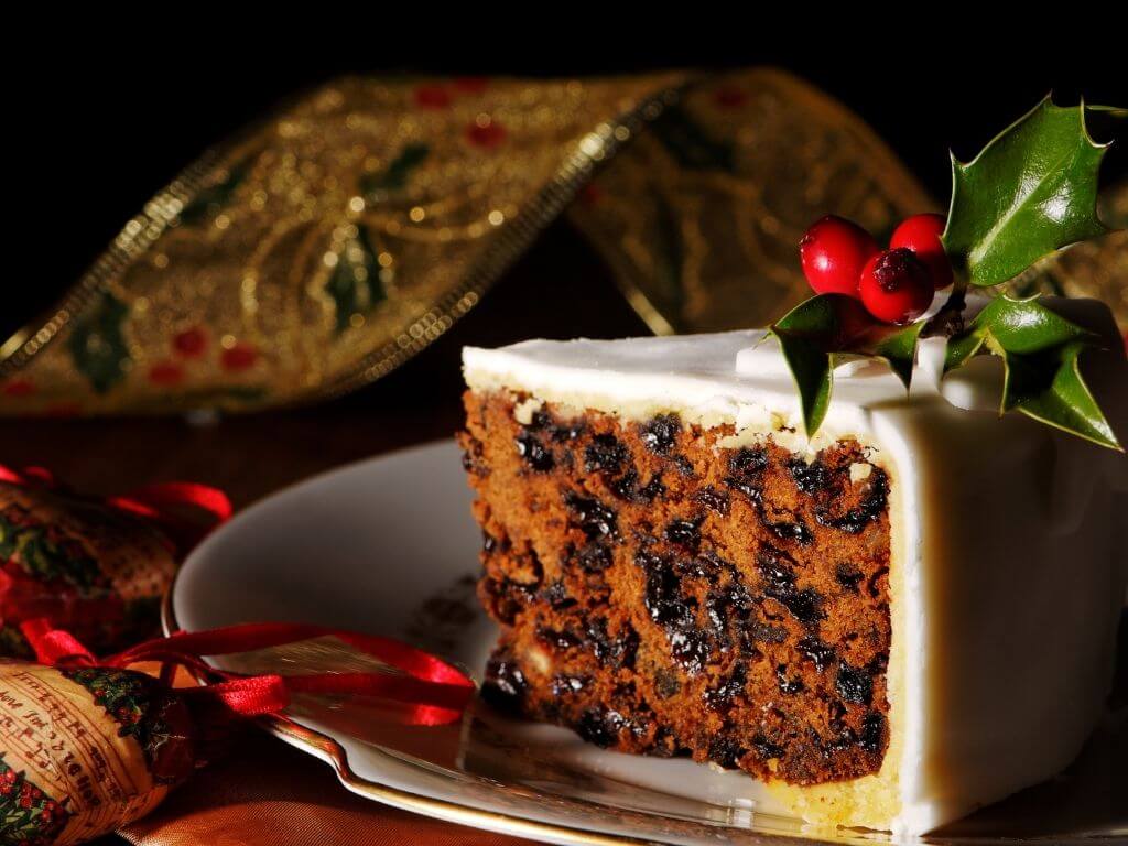 A picture of a slice of traditional Christmas Cake decorated with white icing and holly