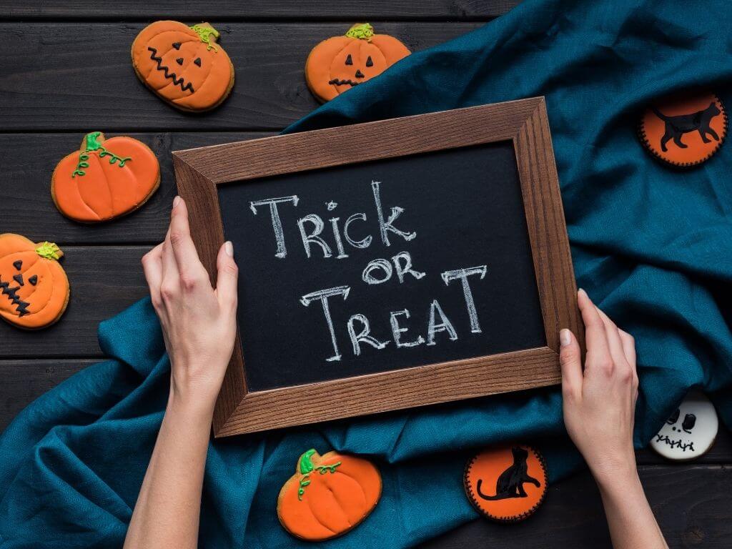 Blackboard saying Trick or Treat surrounded by pumpkin and Halloween decorations