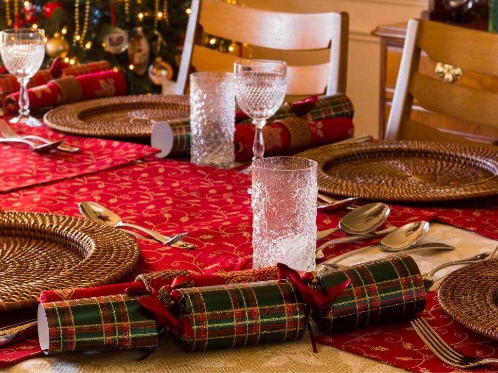 A picture of a Christmas Dinner Table with glasses and Christmas crackers