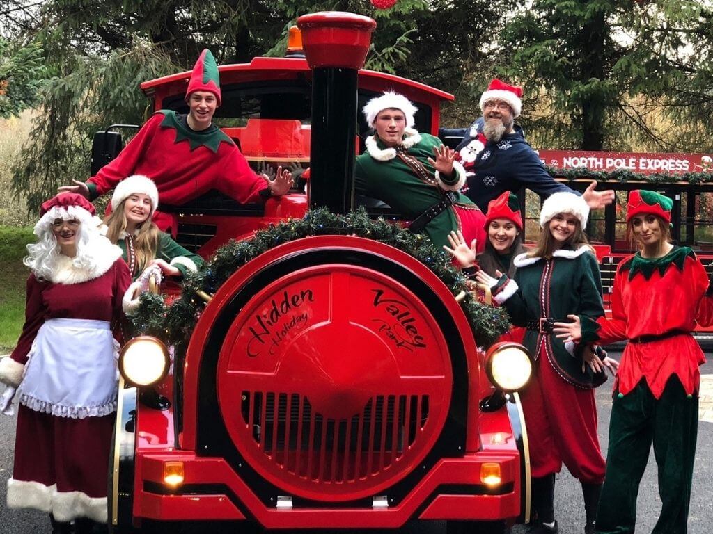 A picture of Elves and Mrs Claus standing on or beside the Hidden Valley Santa Train