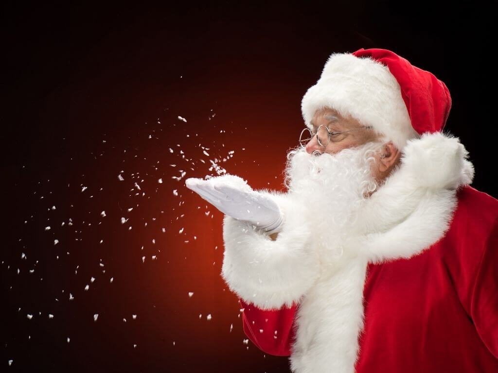 A picture of a Santa blowing snow against a red background
