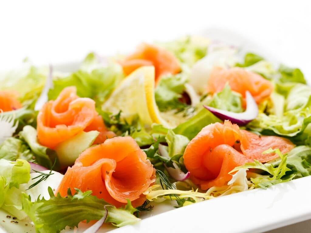 A picture of a bed of lettuce leaves with Smoked Irish Salmon