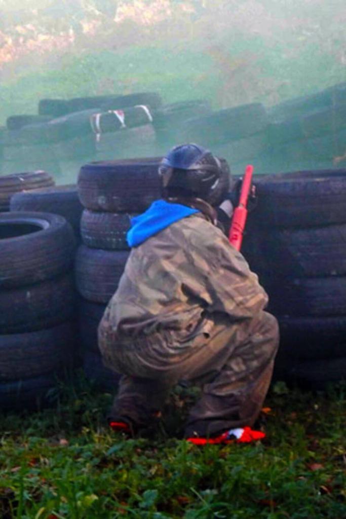 Someone crouched behind a wall of tyres playing Splatball at Westport Adventure Park