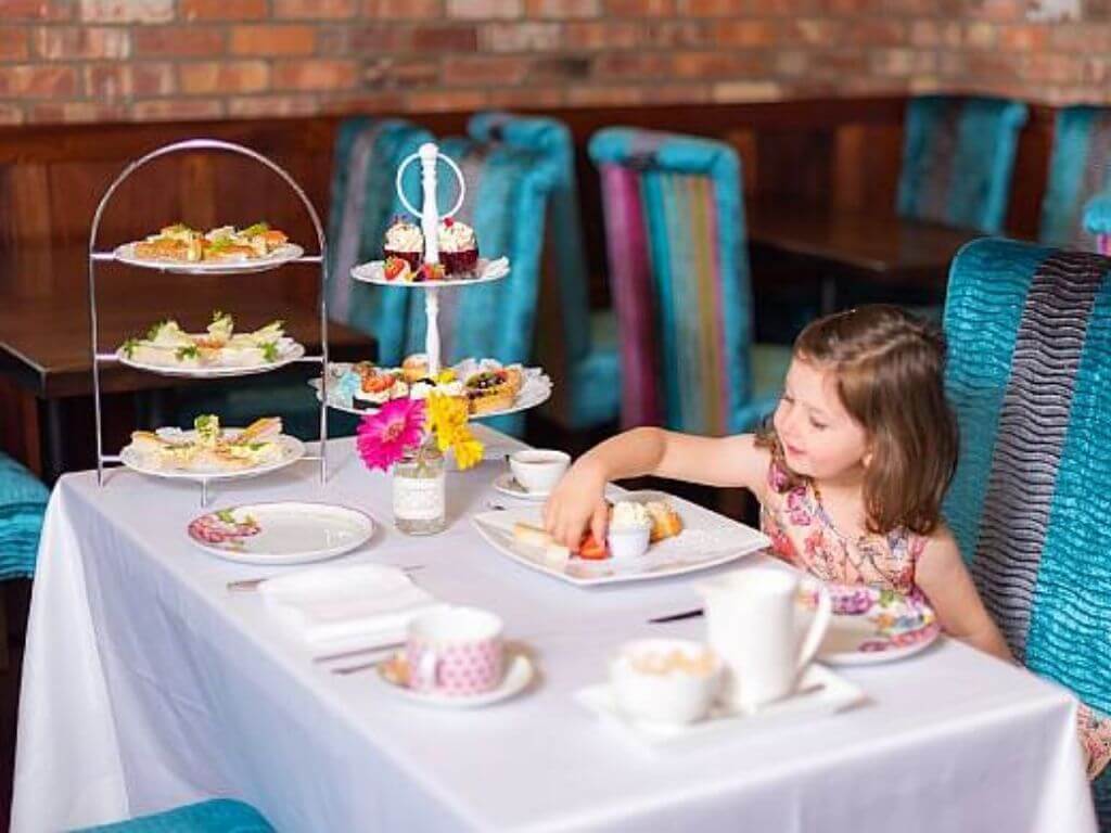 A table set with a girl sitting on a chair ready for the Children's Afternoon Tea at the Maritime Hotel, Bantry