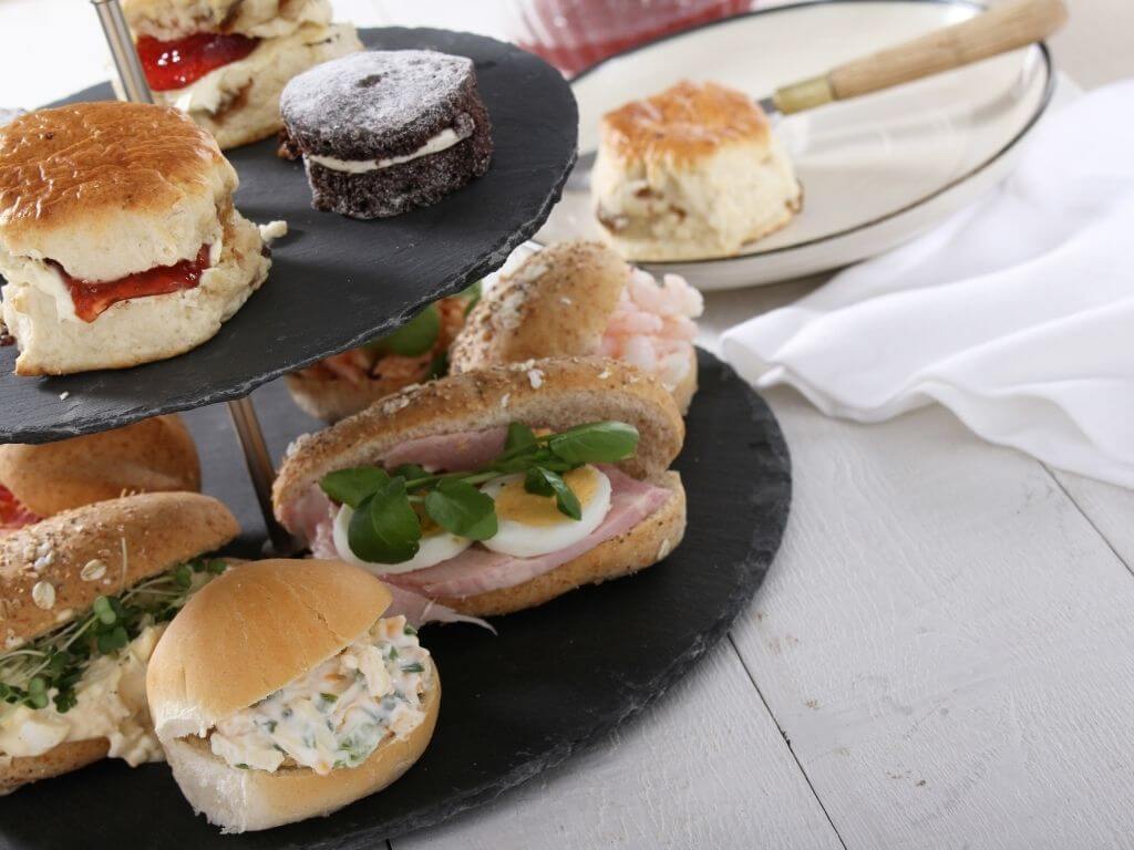 A close-up of sandwiches and treats set on two tiers for afternoon tea