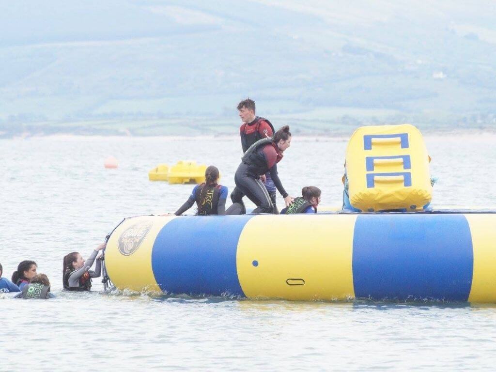 A picture of some people climbing onto an aqua inflatable in the sea at Sandy Bay Splash Sports Aqua Park