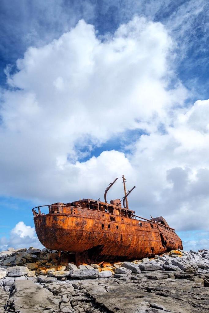 A picture of the Plassey Shipwreck on the Aran Islands at low tide with blue skies overhead with fluffy white clouds