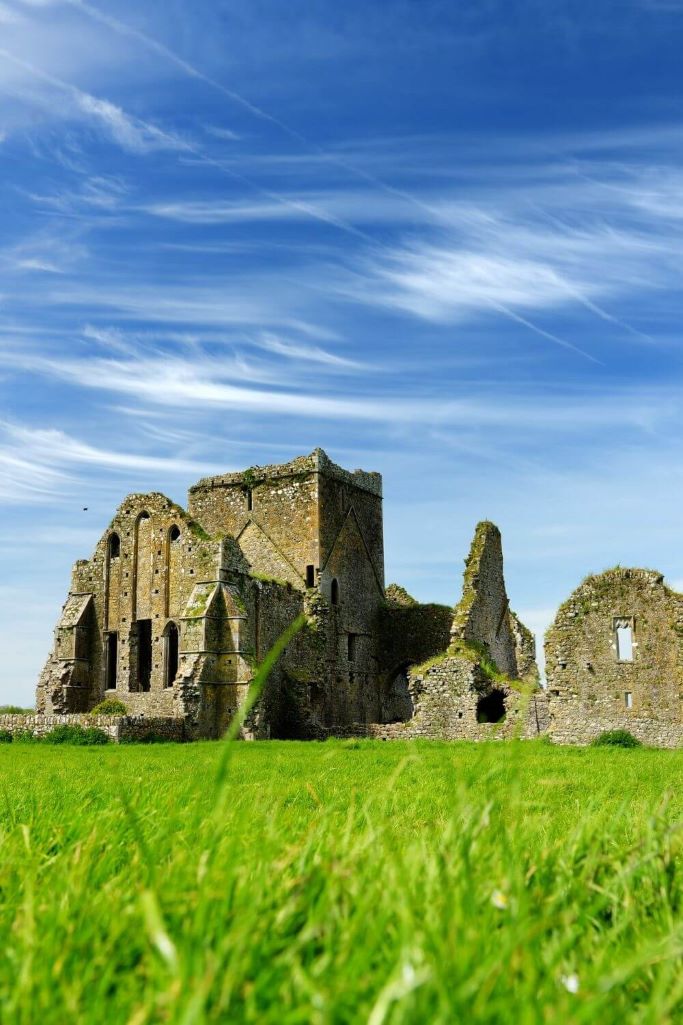 A picture of the ruins of Hore Abbey, Tipperary with green grass in the foreground and blue skies overhead