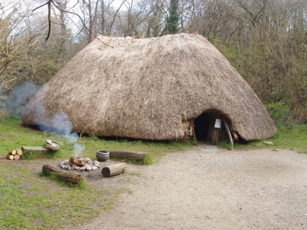 A replica crannog-type building and a smoking fire outside at the Irish National Heritage Park in Wexford, Ireland