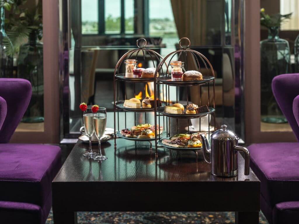 A table set with two 3-tiered cake stands, two glasses of bubbly and a tea pot for the Galmont Hotel afternoon tea