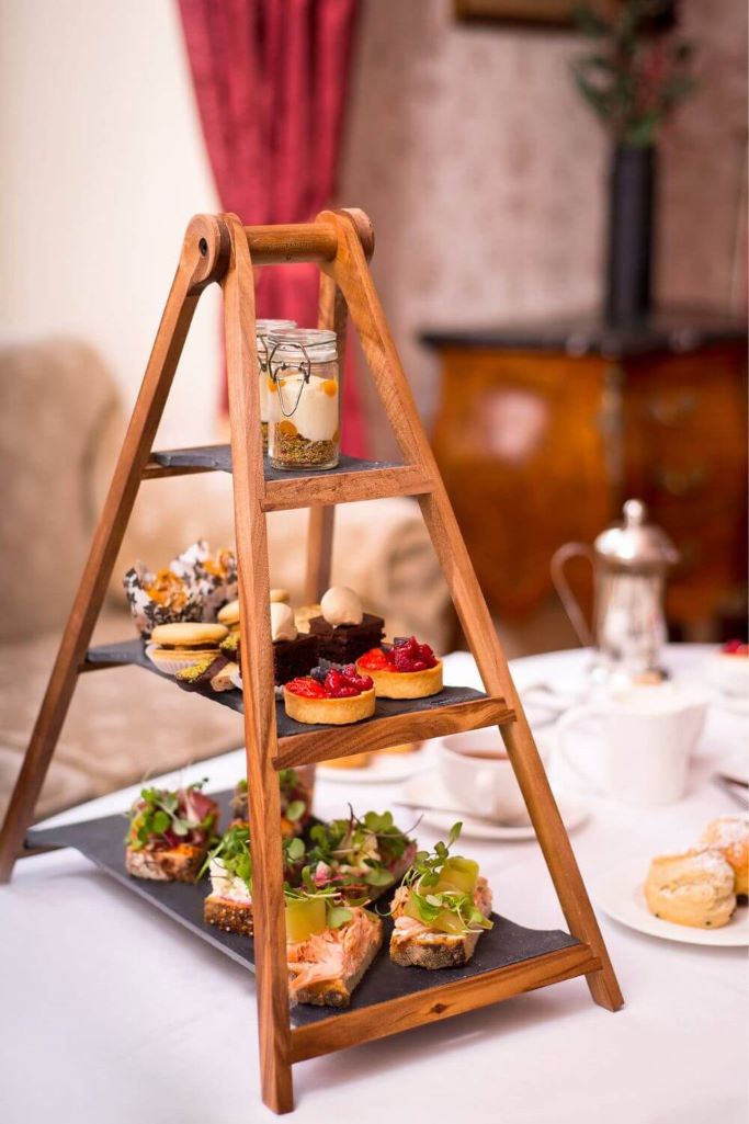 A wooden 3-tiered cake stand set on a table for the Ardilaun Hotel afternoon tea