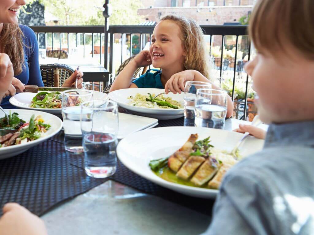 A boy and girl smiling at their mum in a restaurant during a meal