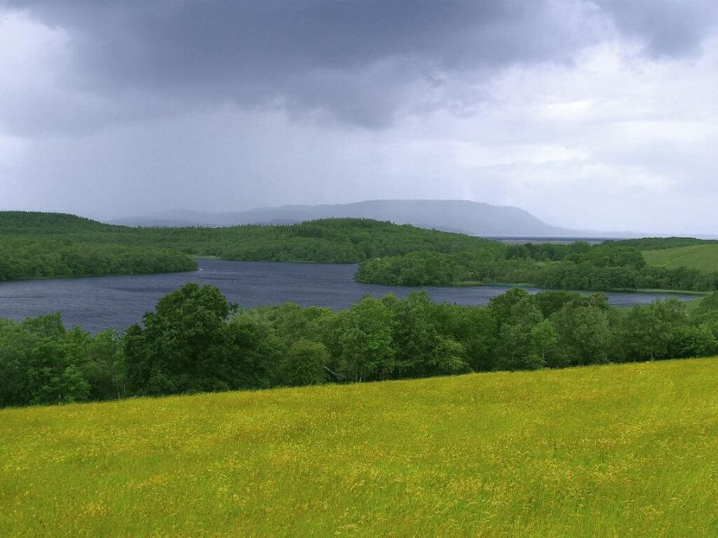 A picture looking over Lough Erne, Northern Ireland with grassy fields in the foreground and mountains in the background