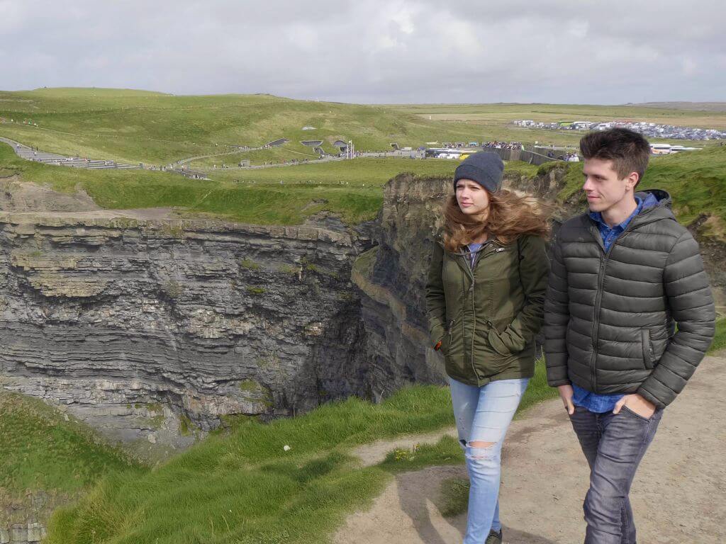 Two people walking along some cliffs in Ireland