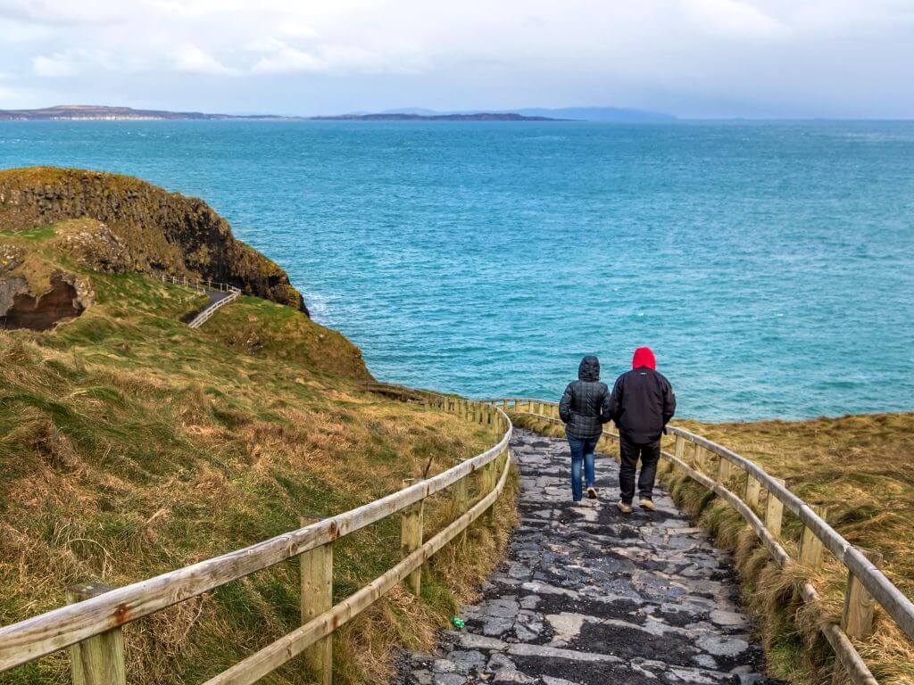 A picture of two people wlaking down steps in Ireland towards the sea