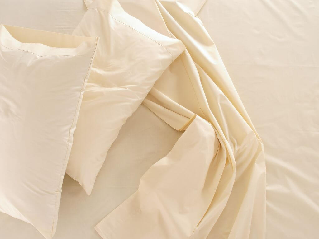 A picture of a bed top sheet and two pillows on a bed