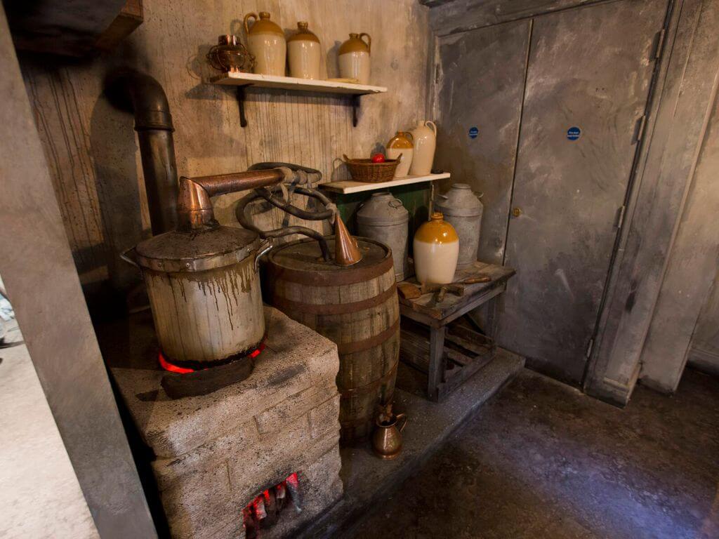 A picture of an old wooden stil beside a brick fire depicting how Irish whiskey was traditionally made years ago at the Irish Whiskey Museum in Dublin