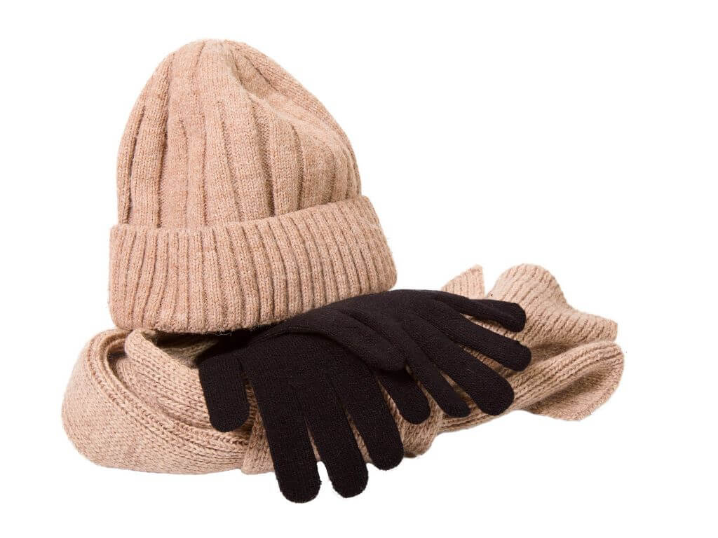 A picture of a beige woollen hat and scarf and a set of black woollen gloves, essentials to pack for Ireland during winter, spring and autumn