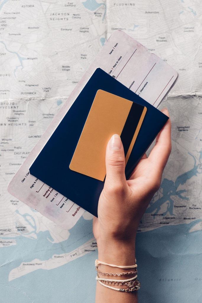 A picture of someone holding a set of travel documents including boarding cards and a passports in front of a map