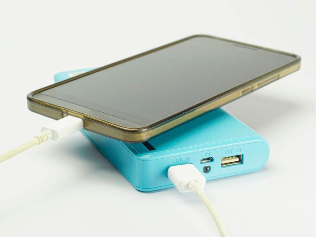 A picture of a mobile/cell phone connected toa blue portable phone charger