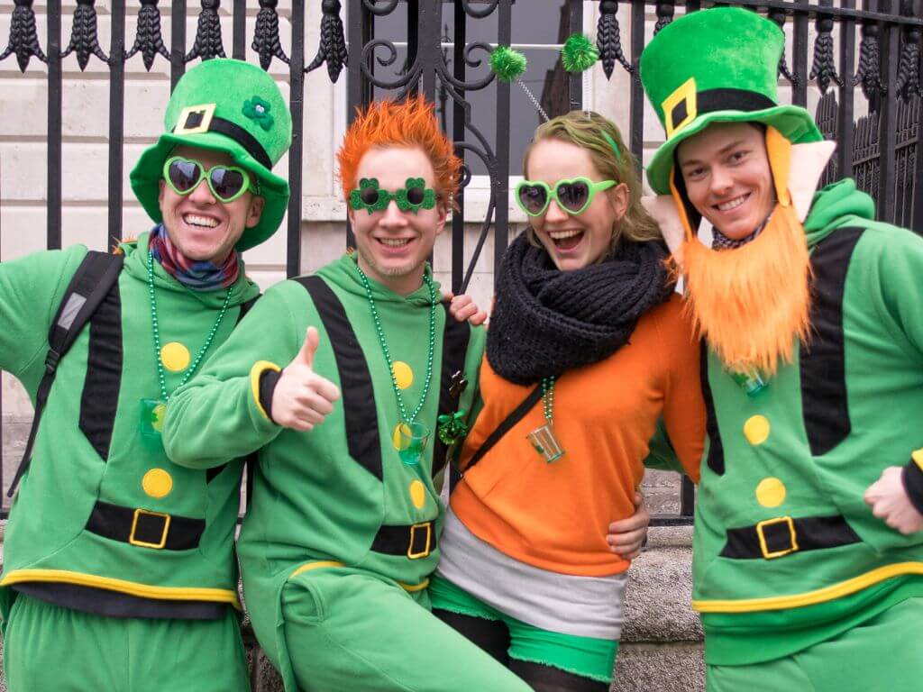 A picture of four revellers in Dublin celebrating St Patrick's Day, all dressed in green, white and orange