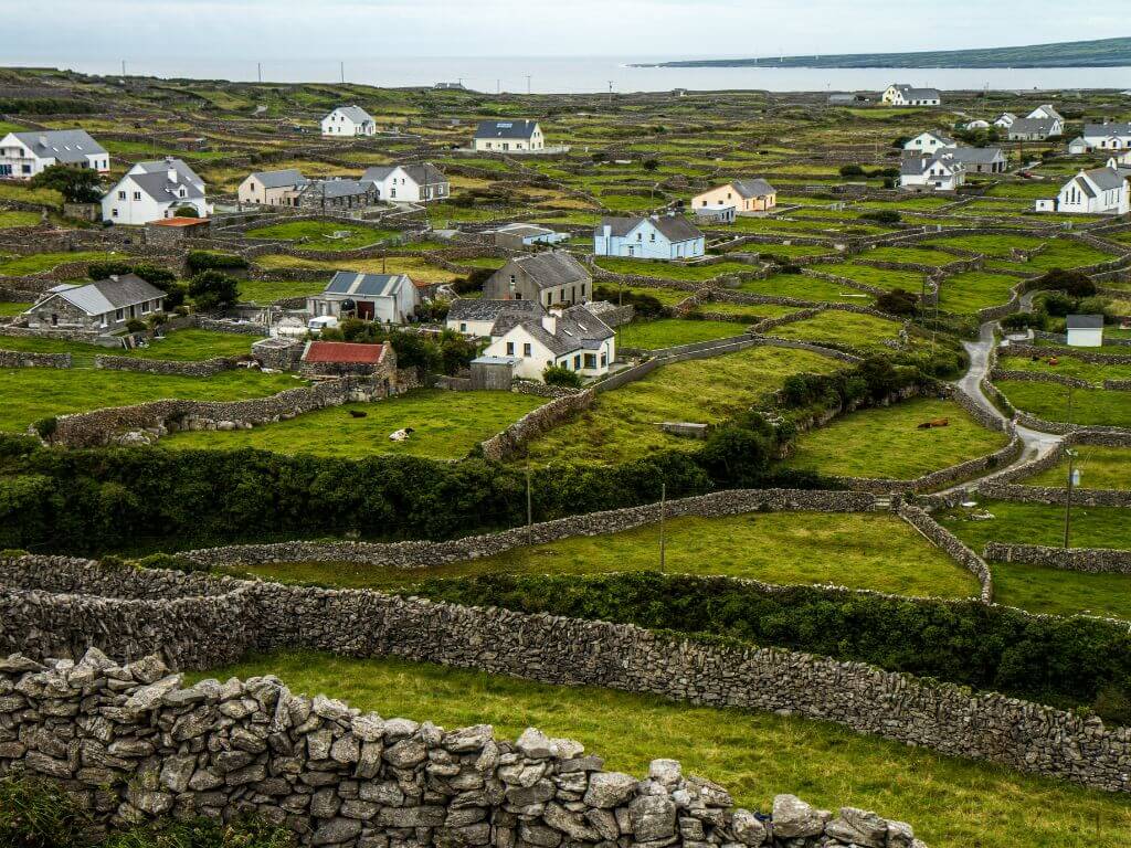 A picture of the Irish countryside with lots of stone walls denoting boundaries and houses and cottages dotted here and there