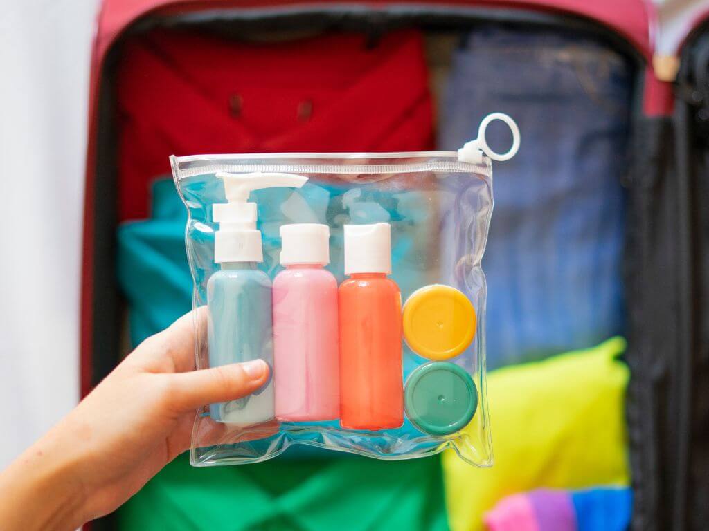 A picture of someone holding up a clear plastic bag containing travel-sized toiletry bottles