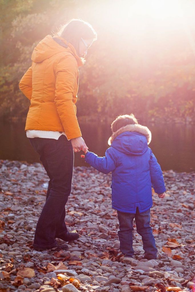 A picture of a woman and young boy standing on some stones wearing winter coats