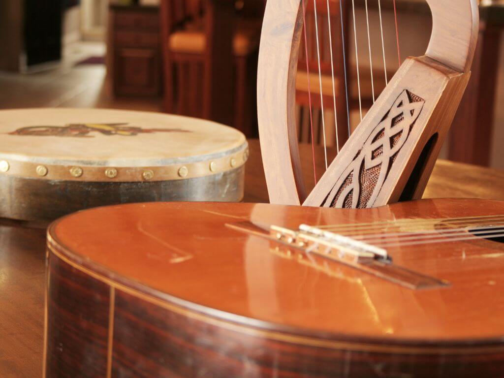 A close up picture of some music instruments used in traditional Irish music including a harp, bodhran and guitar