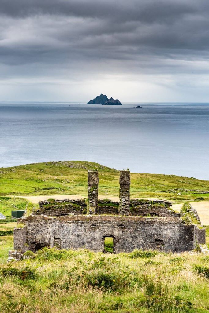 A picture of a ruined house in the foreground, looking out across the sea to the Skellig Islands, part of the Wild Atlantic Way in Ireland