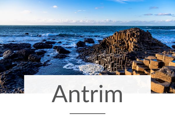 A picture of the sea lapping around the Giant's Causeway and text overlay underneath saying Antrim
