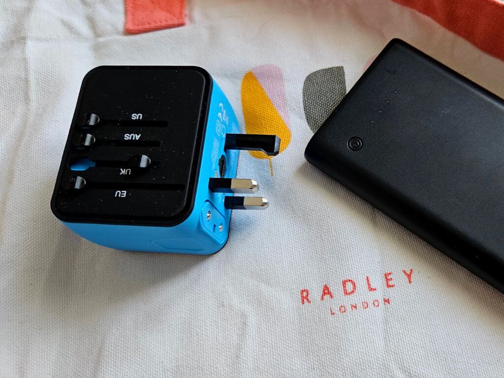 Travel adapter and power bank on a Radley tote bag.